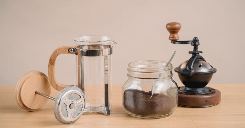 Stylish coffee brewing setup with a French press and vintage coffee grinder on a wooden table.
