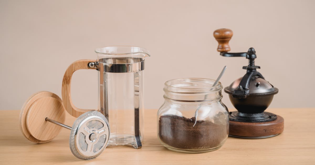 Stylish coffee brewing setup with a French press and vintage coffee grinder on a wooden table.