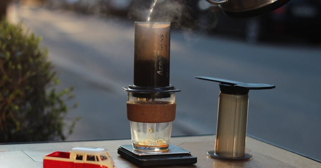 Aeropress coffee setup on table with hot water pouring from kettle and toy car nearby.