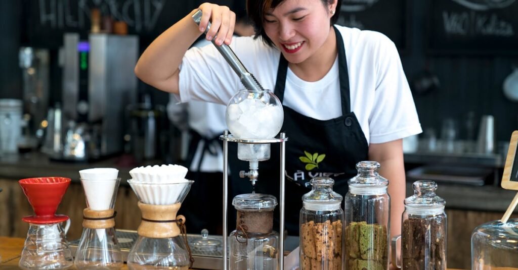 Smiling barista using coffee equipment in a trendy cafe setting.