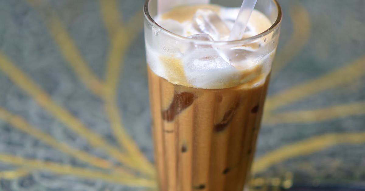 A delicious iced coffee with straw, served in clear glass on a colorful artistic table surface.