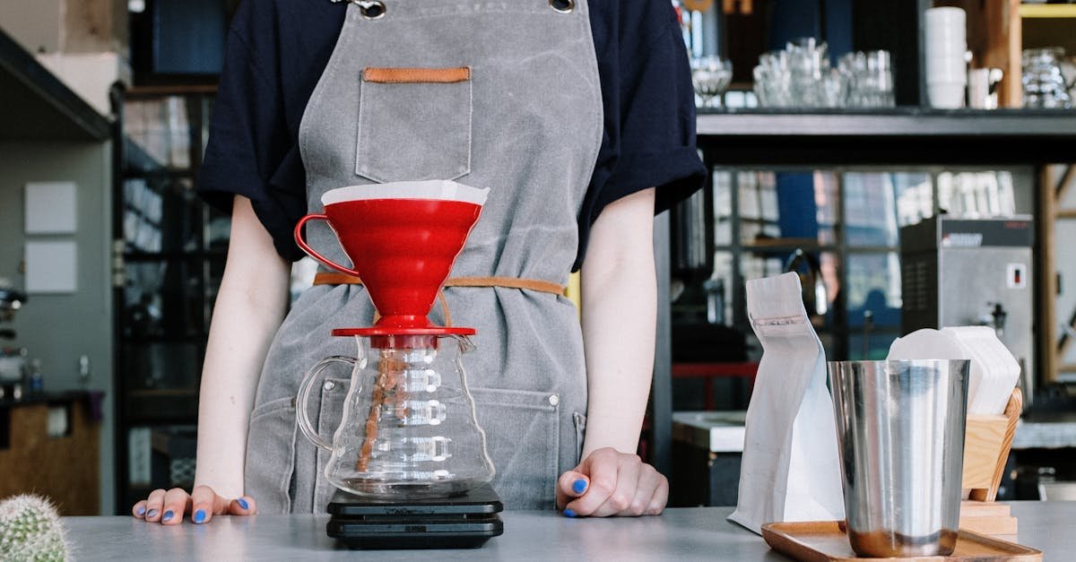 Barista in apron making pour over coffee with v60 dripper in modern coffee shop.